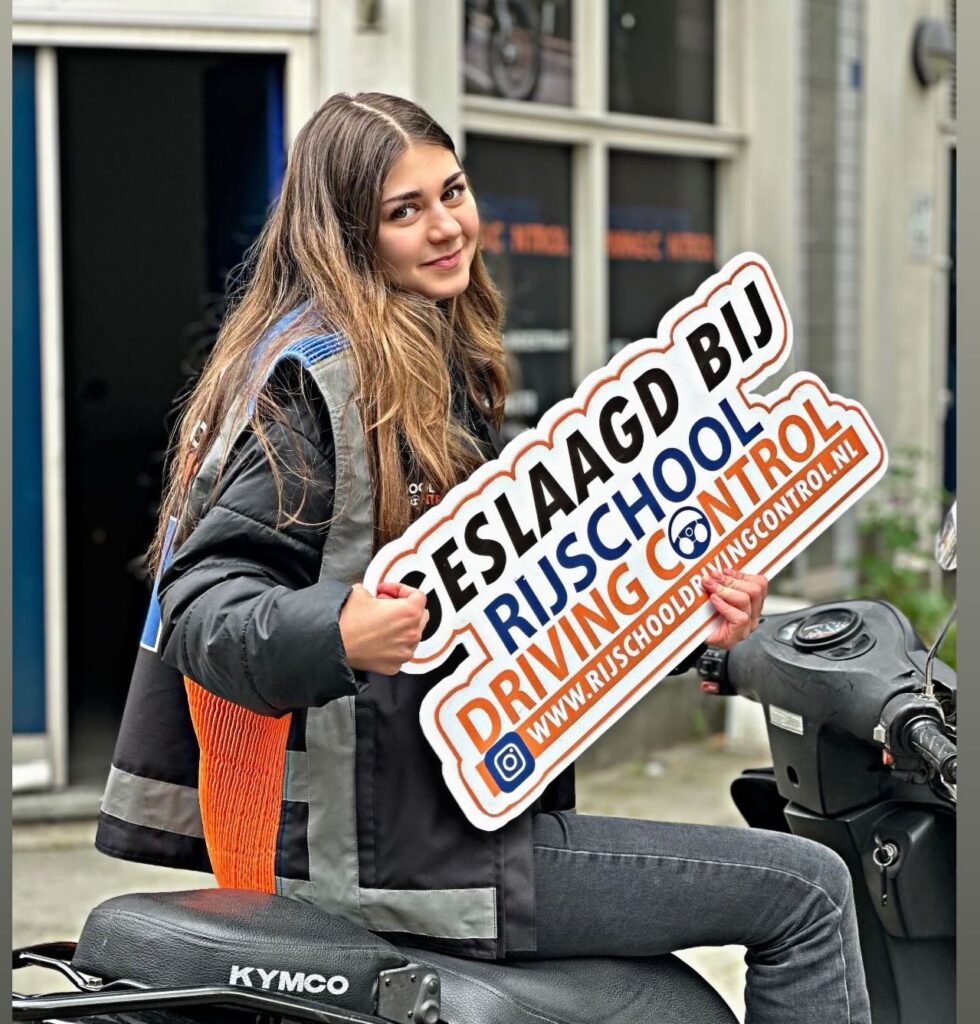 Geslaagde scooterleerling met Geslaagd-bord na scooterexamen Rotterdam bij Rijschool Driving Control