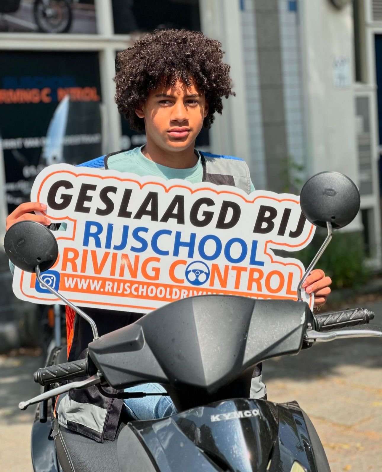 Geslaagde scooterleerling op scooter met Geslaagd-bord Rijschool Driving Control Rotterdam